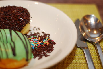 Two donuts with sprinkles are served on a white plate