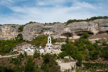 Fototapeta premium Anastasia Uspensky cave monastery in Bakhchysarai. Unique ancient cave monastery. Orthodox Church with white tower on the background of a rock.
