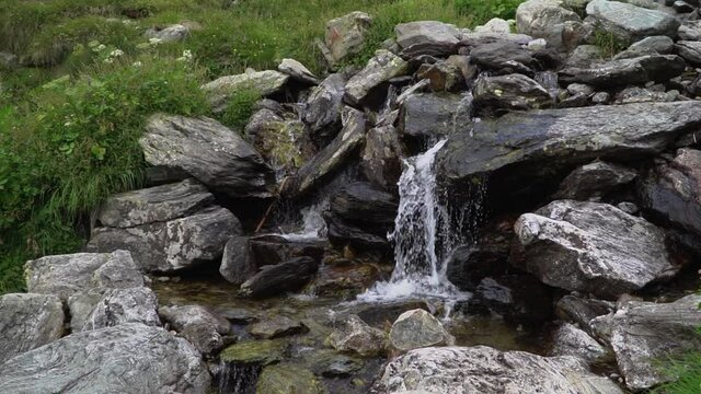 Static slow motion shot for natural waterfall cascade while water runs down between wet big rocks