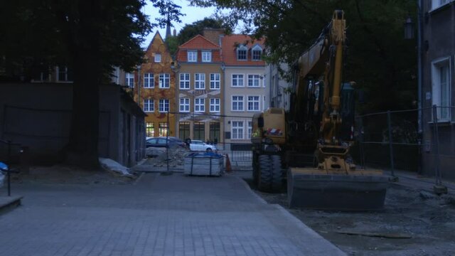 sidewalk renovation at Gdansk Poland city , yellow  digger on front and typical traditional polish buildings at background