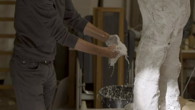 Artist placing wet plaster wrap on sculpture