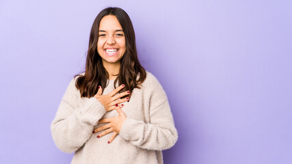 Young mixed race hispanic woman isolated laughs happily and has fun keeping hands on stomach.