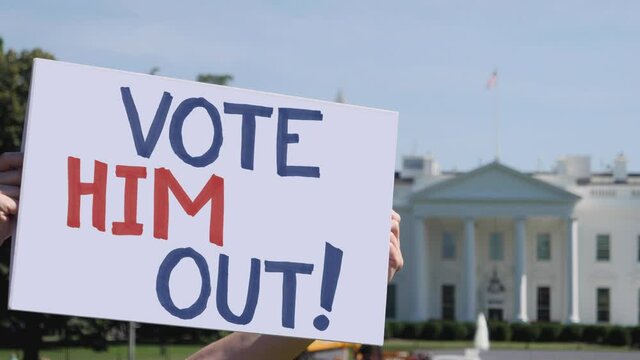 WASHINGTON - Circa September, 2020 - A man holds a handmade VOTE HIM OUT! election protest sign outside the White House.	