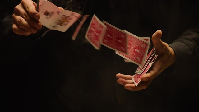 Close-up of a Magician's Hands Performing Card Trick . Throwing and Catching Cards in the Air on black Background with smoke . Card Mechanic .  Shot on ARRI Alexa cinema camera in Slow Motion . 200fps