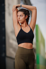 doing stretches before running. Young slim athlete girl stretching on the street in sportswear