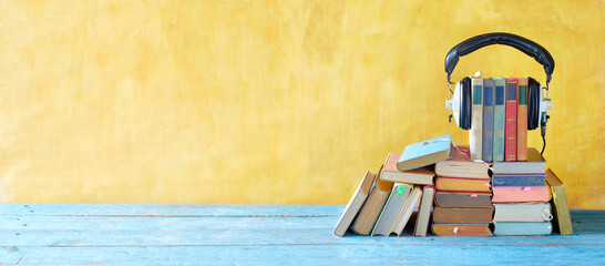 audio book concept with large heap of books and vintage headphones, good copy space