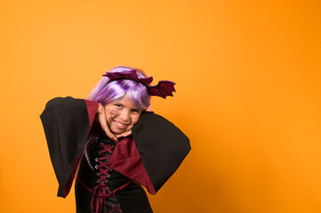 Enthusiastic little girl in a witch costume . Person posing on a yellow background in the studio. Copy space. High quality photo