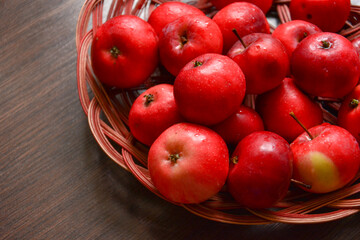 Red apples in a wicker plate on a dark background