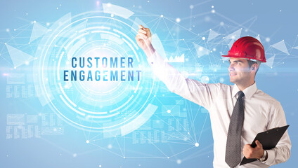 Handsome businessman with helmet drawing CUSTOMER ENGAGEMENT inscription, contruction business concept