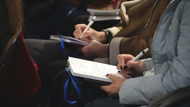 Unrecognizable student in black shirt writing notes on lecture. Professional journalist interviewing and writing text to notebook. Man keep diary. Concept of education. Slow motion Close up