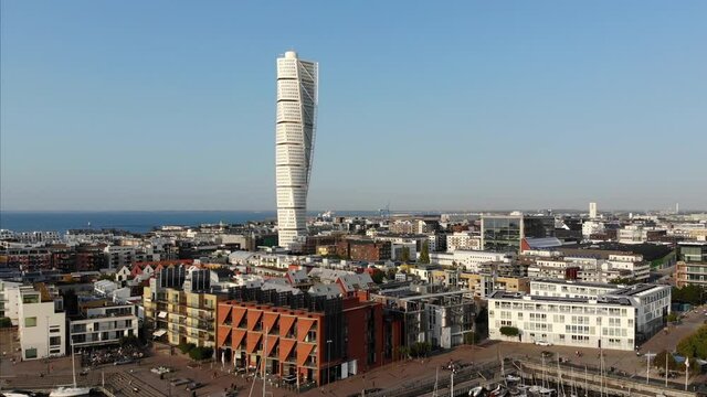 Upwards flying drone getting nice view of v&auml;stra hamnen, turning torso in Malm&ouml;, Sweden, summer evening