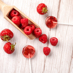 Homemade lollipops made from natural dehydrated strawberries and raspberries on a white wooden background. Healthy vegan vegetarian food with no sweets.