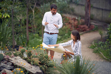 Young female guide showing the botanical garden map to a young male visitor