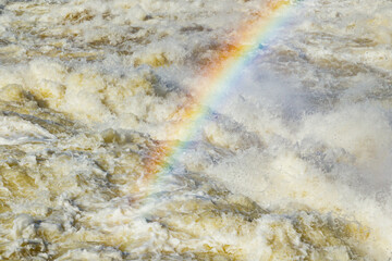 Splashing water waves with rainbow on the fast river