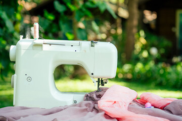 sewing machine outdoors in summer park against the background of the wooden house