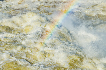 Splashing water waves with rainbow on the fast river