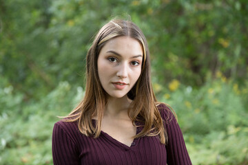 Fototapeta premium Portrait of a beautiful brunette outdoors on a green forest background.