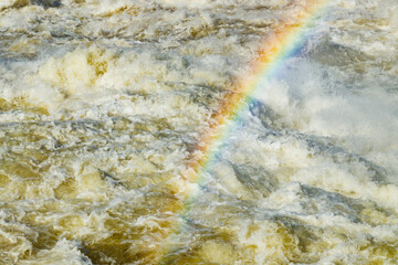 Splashing water waves with rainbow on the fast river