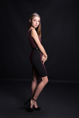 Fototapeta na wymiar Beautiful brunette in an elegant dress on a black background.