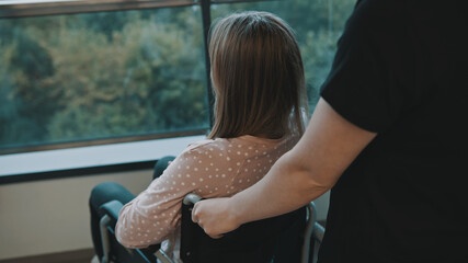 Carer and young woman in the wheelchair on the balcony. High quality photo