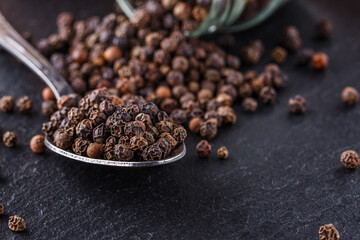 aromatic black pepper on a dark stone background