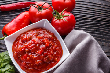 Fresh tasty tomato sauce on rustic wooden background