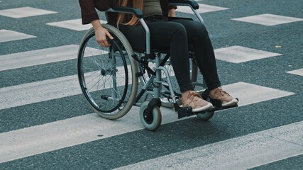 Young unrecognizable handicapped woman in wheelchair crossing street carefully. High quality photo