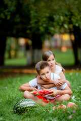 sister hugs brother who eats watermelon