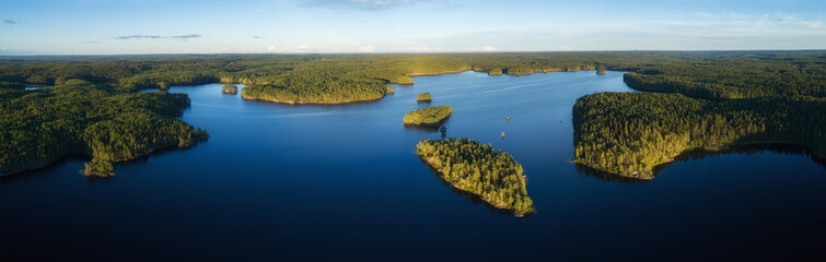Aerial panorama of beautiful lake Haukkajarvi, islands and green forest at sunset. Helvetinjarvi national park. Finland.