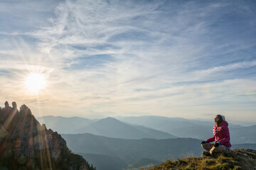 Naklejka premium Young woman meditating on a mountain peak