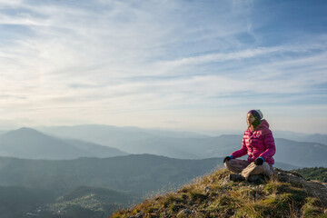 Naklejka premium Young woman meditating on a mountain peak
