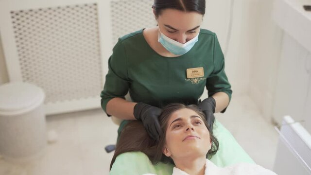 Female Mesotherapy Doctor With Mask on Mouth and Gloves on Hands Massage Patients Hair After Mesotherapy Injection Treatment. Light Camera Movement