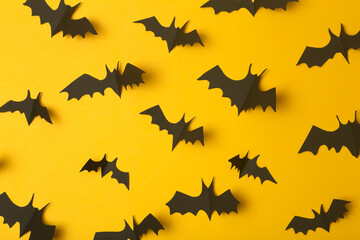 Halloween background. Black bats cut from paper on a yellow background. Halloween decor and decorations for the holiday, copy space.