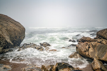 Fototapeta na wymiar Magische-Mystisches Meer. Nebel, Fog, Mist, Wolken, Wellen, Steine am Strand mit Blick auf den ewigen Ozean.