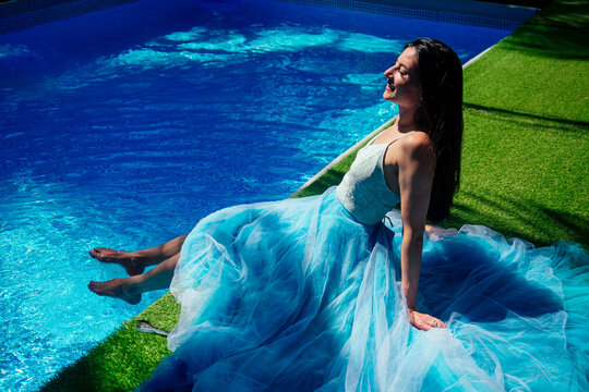 indian woman posing in blue long dress near swimming pool