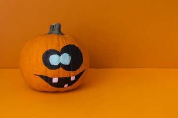 pumpkin with a funny expression on an orange background, a shot for the day of all the dead, halloween decorations