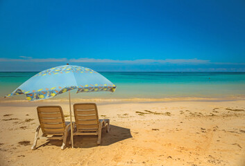 Tropical destination beach with two chairs, parasol, deep blue ocean and warm weather in Cuba