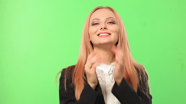 Blond middle aged woman in business clothe say I love you in Russian. Woman show heart symbol and blow a kiss. Woman standing on the green screen. High quality FullHD footage