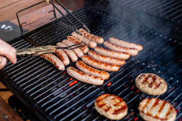 Man at a barbecue grill with smoke.Grilling sausages on barbecue grill. BBQ party.Delicious german sausages or bratwurst .Selective focus.