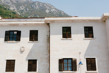 Fototapeta na wymiar The house is white with brown windows and shutters against the backdrop of a mountainous area.