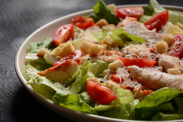 Caesar Salad with grilled chicken, Cheese and Croutons with lettuce, on plate.  Grilled chicken breasts and fresh vegetables in plate. 