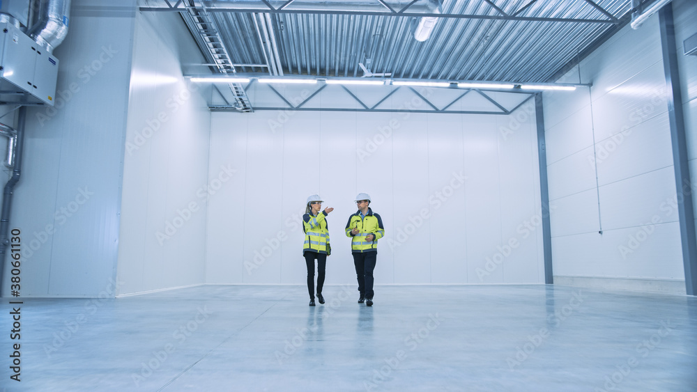 Aufkleber two engineers talking, walking across empty factory floor, inspecting, planning where all the machin