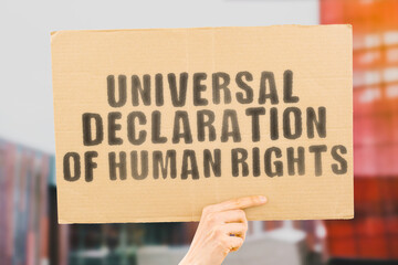 The phrase " Universal Declaration of Human Rights " on a banner in men's hand with blurred background. Equality. Society. Diversity. Conflict. Confrontation. Safety. Security