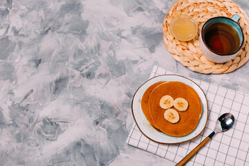 pancakes, honey, tea on a gray background