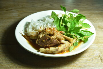 rice noodles dressing with chicken foot and blood curry sauce with fresh vegetable on plate