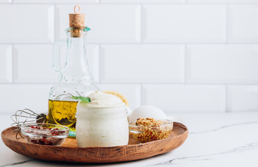 Obraz premium Homemade mayonnaise sauce with ingredient - olive oil, eggs, mustard and lemon on a wooden plate.