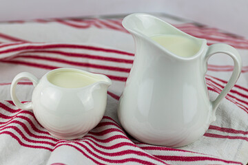 two milk jugs with kitchen tea towel
