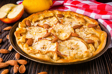 crispy apple galette with almonds on rustic wooden background