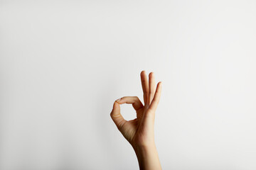 Female hand shows okay gesture from down, on white background with free space for text