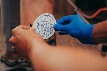 Tattoo artist putting a design on a client's leg.